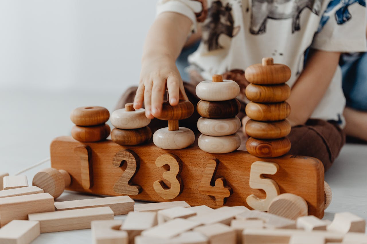 The Art of Drawing Readers In: Your attractive post title goes here Child's hand interacting with wooden educational toys and number blocks indoors.